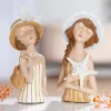 Zwei GILDE Lady Louise Stranddamen aus Kunstharz in cremeweißen, gestreiften Sommerkleidern mit Hüten, Handtasche und Seestern.
